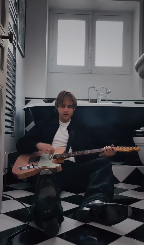 Artist with guitar in bathroom