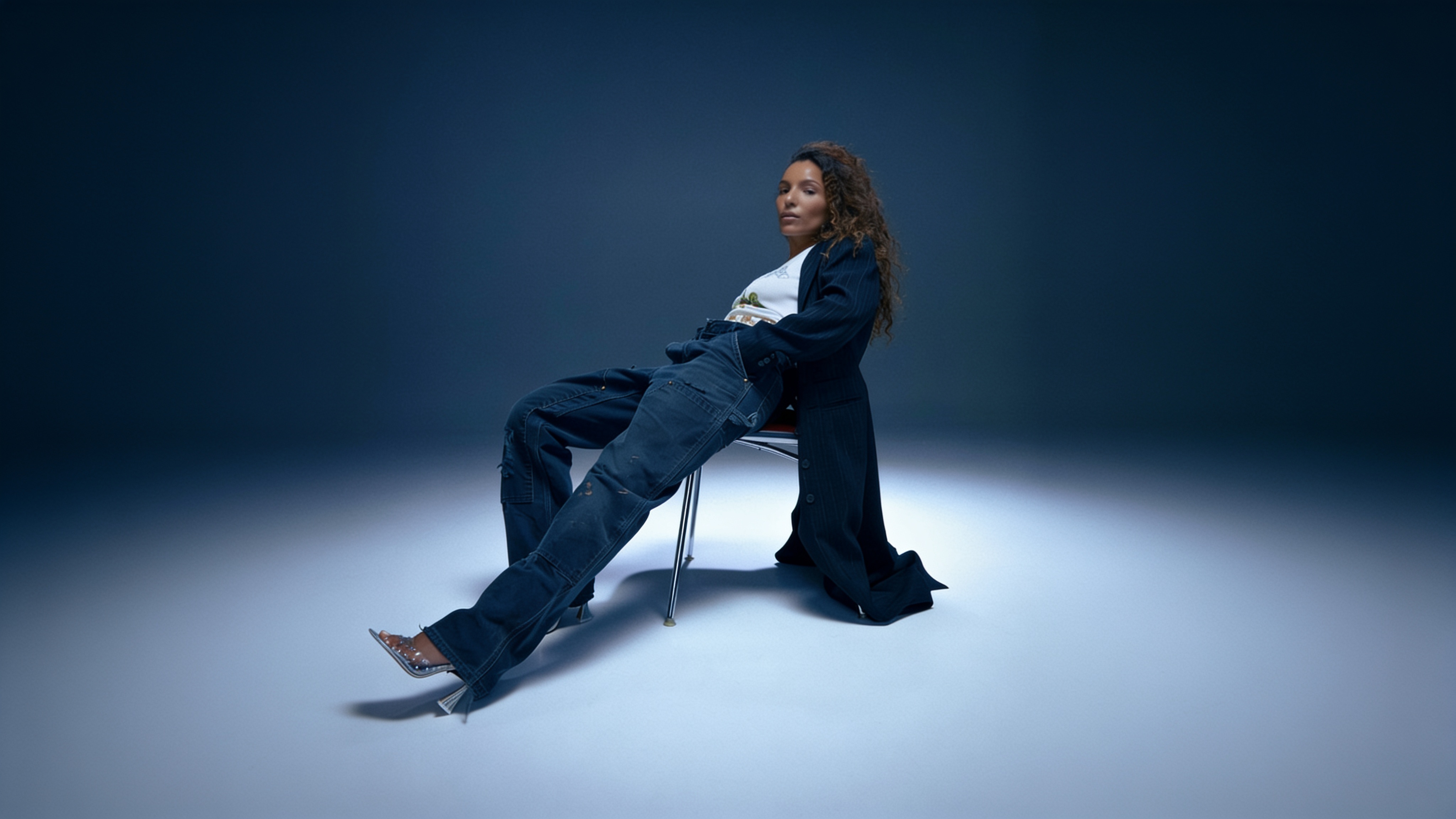 Soane assise sur une chaise dans un studio bleu